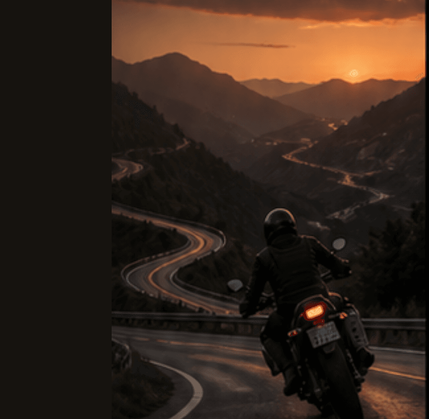 Motorcyclist riding a winding mountain road at sunset